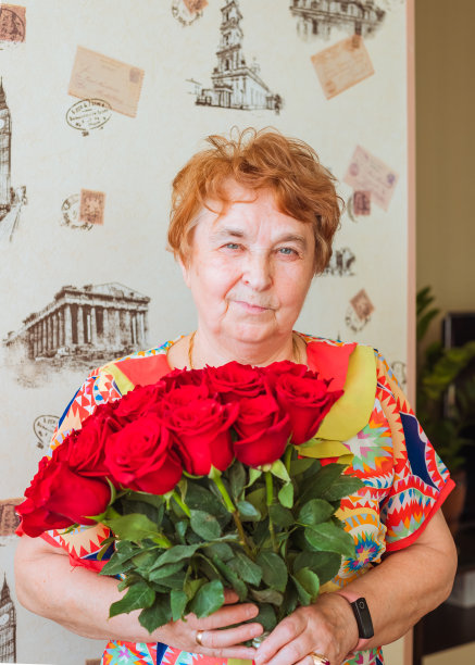 年长的成年公民，年长的高加索白人女性，73岁的祖母拿着红玫瑰花束。生日聚会，母亲节。正面肖像图片下载