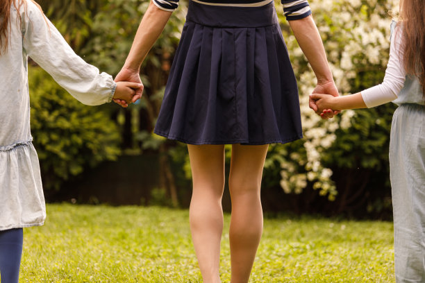 母亲牵着女儿们的手走过绿色的花园图片下载