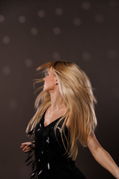 在灰色背景下跳舞的酷年轻金发女郎图片下载