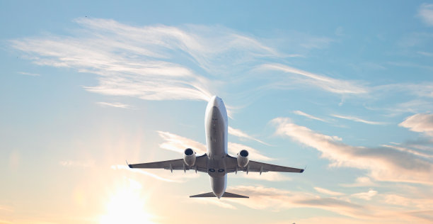 白色的客机在天空中飞行，背后是令人惊叹的云——乘飞机旅行图片下载