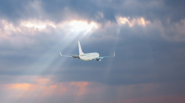 白色的客机在天空中飞行，背后是令人惊叹的云——乘飞机旅行图片下载