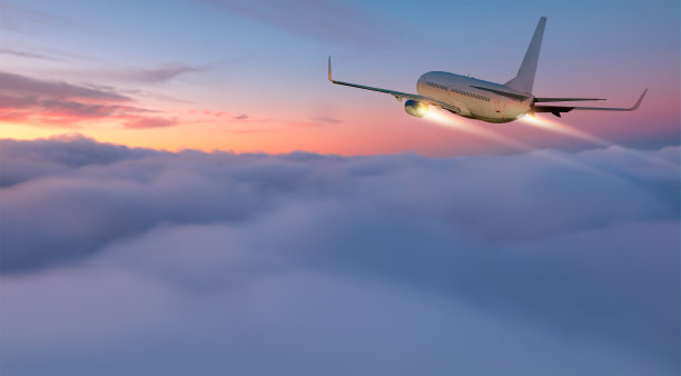 夕阳下飞越热带海域的飞机图片下载