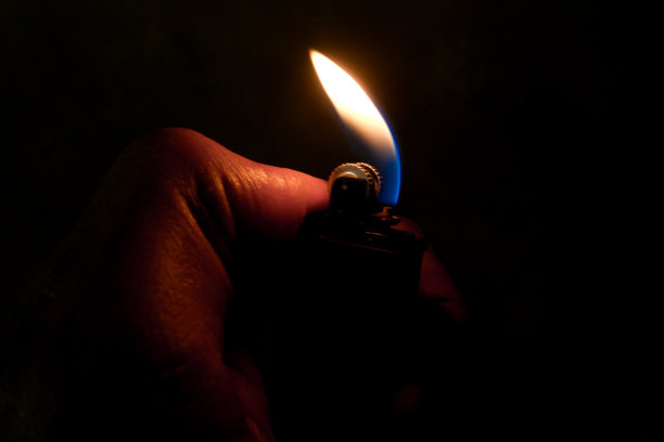 一个手人像在黑暗中用打火机点燃了火。图片下载