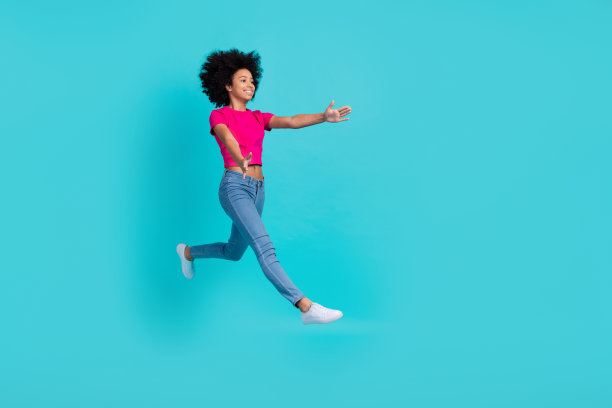 活跃兴奋的女学生的全身侧面照片跳跃冲臂捕捉空白空间孤立在蓝绿色的背景图片下载