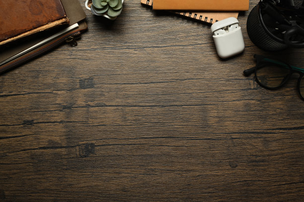 木制办公桌，配有笔记本、眼镜、耳机和盆栽。平铺，顶部视图与复制空间图片下载