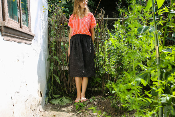 赤脚的女孩穿着漂亮的古着衣服站在老木屋旁边。夏日的乡村风格照片。谷仓或农场附近的院子。图片下载