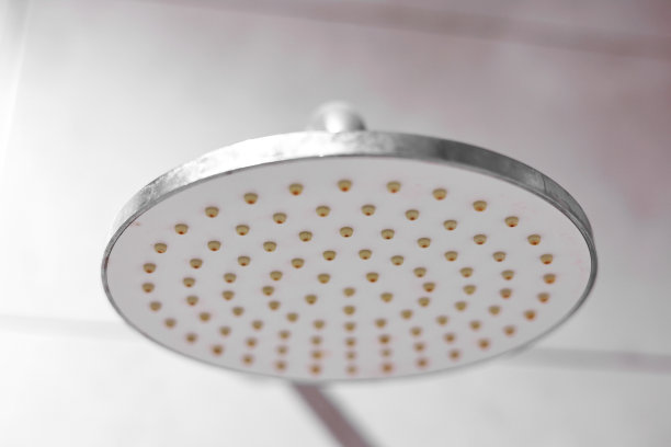 肮脏的钙化圆形淋浴头和淋浴臂，镀铬的龙头，带有铁锈和水垢的水龙头，硬水形成的斑块，特写，底部视图。清洁公司理念。图片下载
