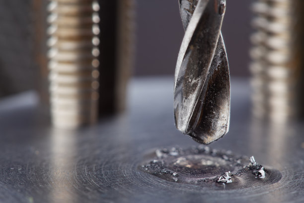 在工业钻床上，金属钻头用润滑油液在钢坯上打孔。金属加工行业图片下载
