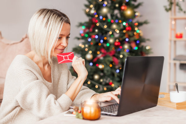 微笑的中年女士拿着笔记本电脑坐在家里买圣诞礼物图片下载