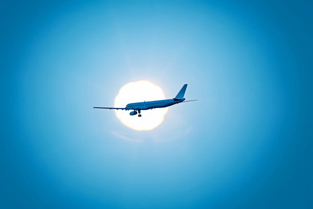 一幅抽象的图形，展示了一架客机在暮色中穿过天空中的太阳。图片下载