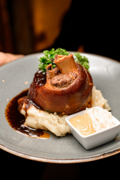 选择性的专注于用香草和女服务员手中的酱汁装饰的炸猪蹄图片下载