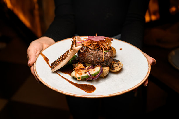 一盘美味的菜肴，有一片烤王香菇和一块油炸的肉，女人手里拿着土豆图片下载