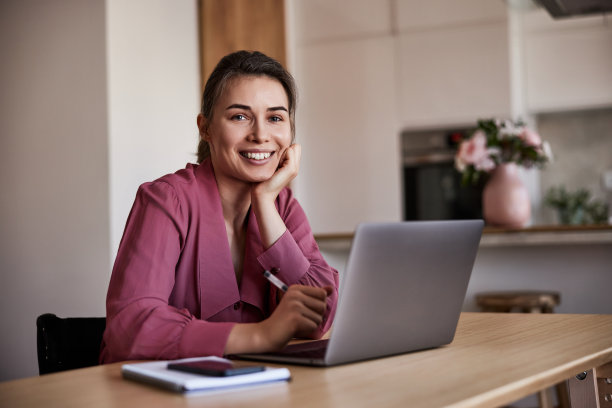 一个坐在轮椅上的漂亮女人在家里用笔记本电脑工作的画像。图片下载