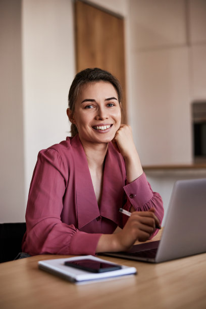 一个快乐的女性自由职业者在家庭办公室里用笔记本电脑工作。图片下载