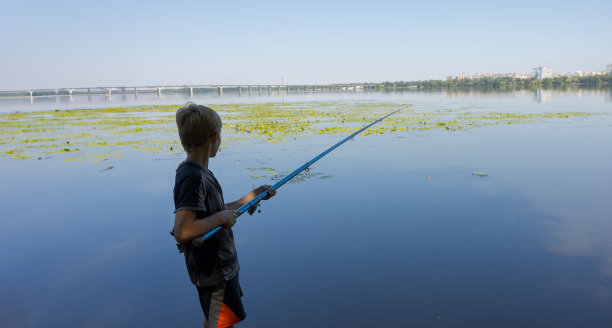 这个男孩夏天在河里钓鱼。图片下载