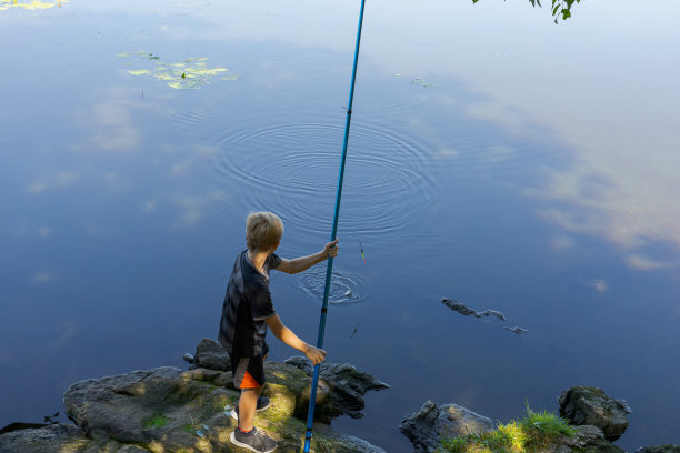 这个男孩夏天在河里钓鱼。图片下载