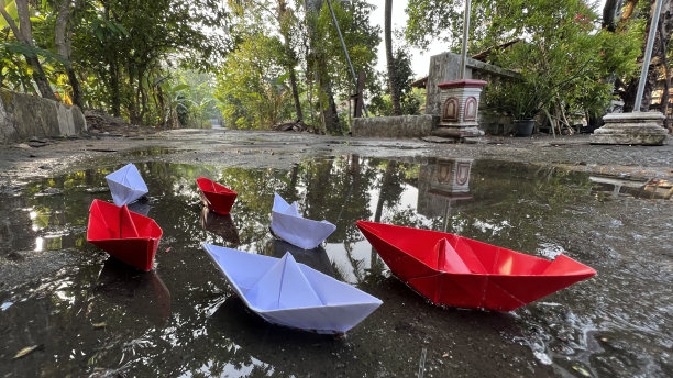 红白相间的纸船漂在水面上。图片下载