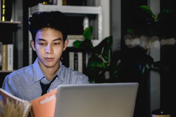 在办公室使用笔记本电脑的亚洲青年男性职员图片下载