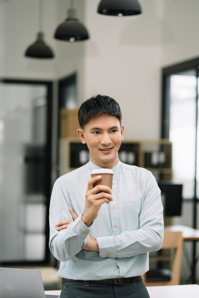 商人端着一杯咖啡站在办公桌前放松人在工作时感到平静图片下载
