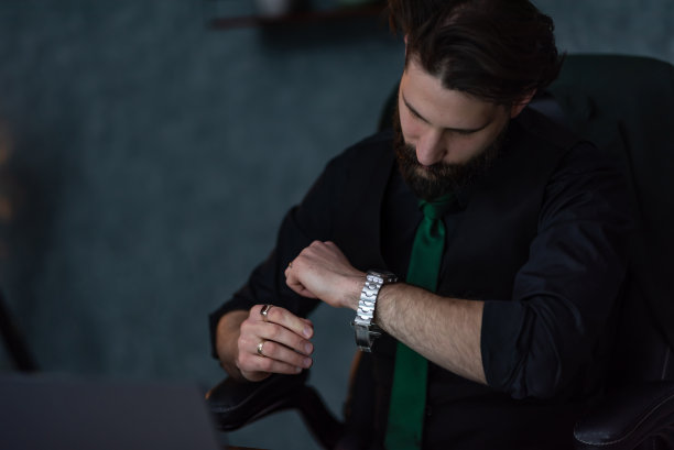 年轻的商人在办公室看着他的手表图片下载