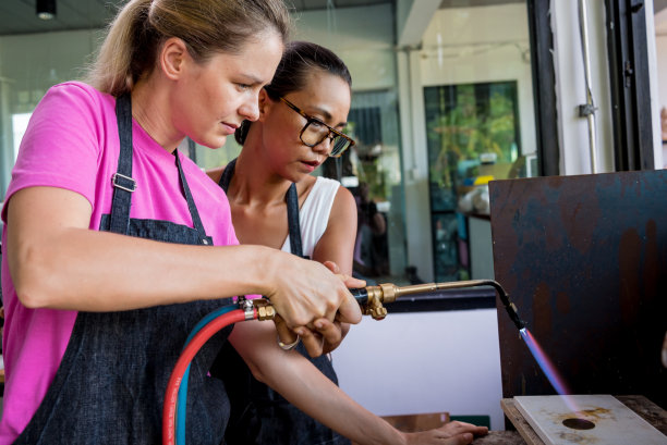 珠宝师教师和学生在车间使用燃烧器图片下载