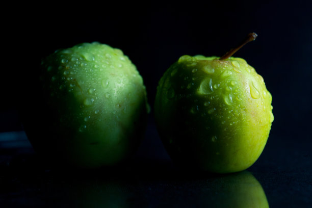 黑色背景上的青苹果，水滴，艺术光图片下载