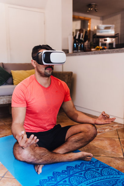在拉丁美洲的墨西哥，一名拉丁男子正在家中使用虚拟现实耳机进行冥想。积极的西班牙人在公寓里用VR现代技术练习瑜伽图片下载