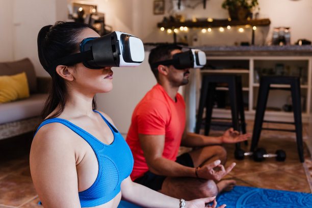 拉丁美洲墨西哥，一对拉丁夫妇在家中使用虚拟现实耳机进行冥想。积极的西班牙人在他们的公寓里用VR现代技术练习瑜伽图片下载
