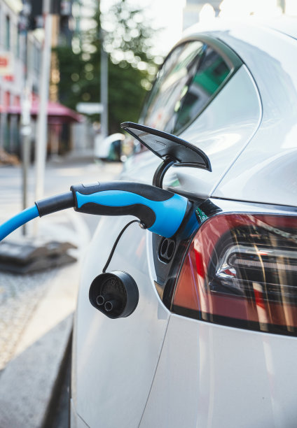 在路边公共车站给一辆白色电动汽车充电图片下载