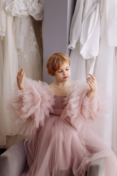 在服装精品店里，一个穿着艳丽的粉色晚礼服的女孩图片下载