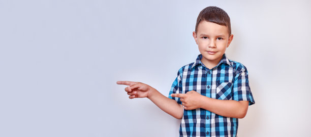 英俊的男孩用手指指着背景上可能的铭文。图片下载