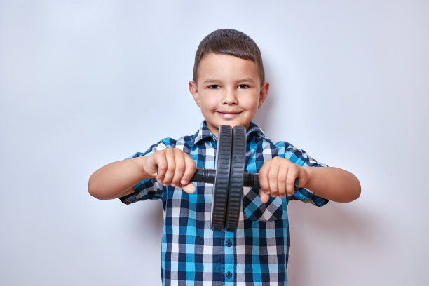 一个小男孩站在那里，手里拿着一个体操轮。健身类。图片下载