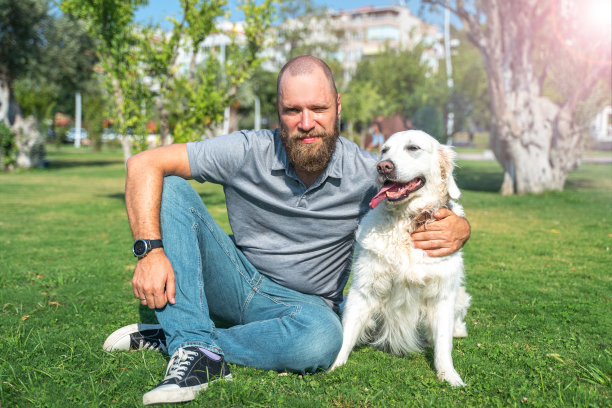 夏天，一名宠物主人和他快乐的宠物金毛猎犬在公园草坪上的肖像。图片下载