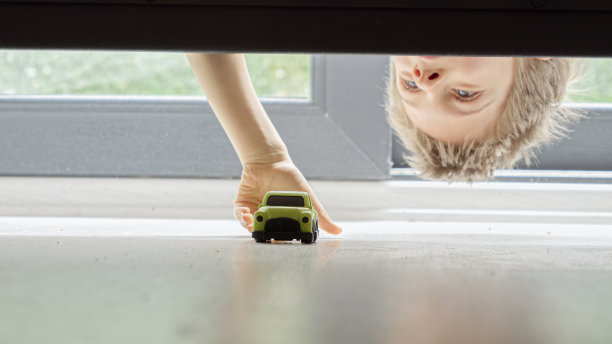 小男孩把他的玩具车丢在床底下找来找去图片下载