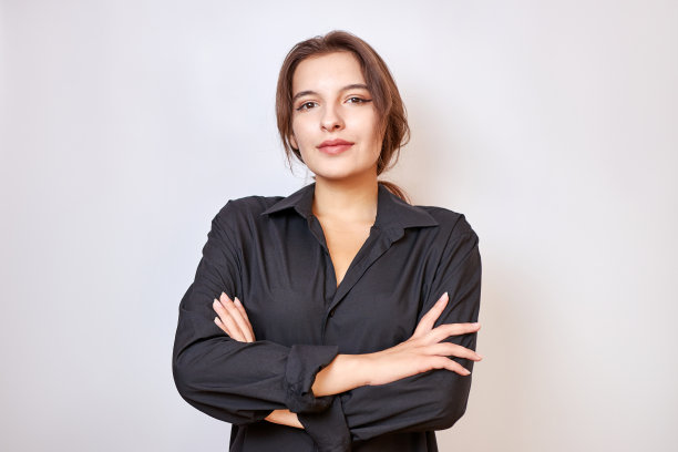 一个穿着黑衬衫的漂亮女孩站在那里，双手交叉在胸前。图片下载