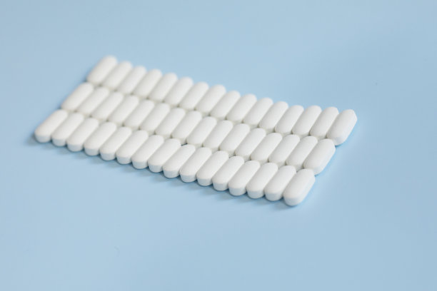 蓝色背景上有很多药片。白色药丸散落在蓝色背景上。图片下载