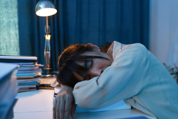 年轻的女商人深夜在家庭办公室的办公桌前睡觉。劳累过度，劳累的女员工在工作时睡着了图片下载