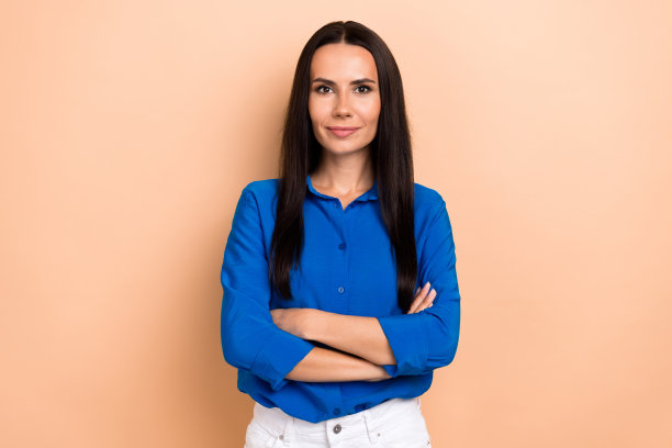 照片中办公室经理的肖像女士抱着双臂，穿着时髦的休闲装，蓝色衬衫，与世隔绝的米色背景图片下载