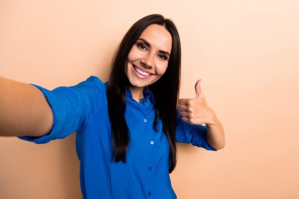 可爱的漂亮女孩穿着蓝色时尚的衣服，在米色背景上展示了强烈的积极反馈图片下载