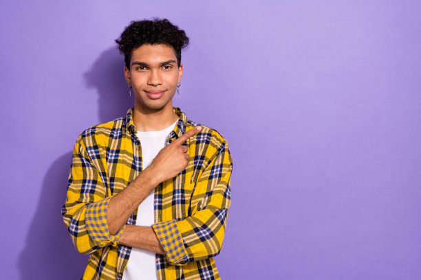 照片的好心情开朗的家伙与耳环穿着格子衬衫表明在销售空间孤立的紫色背景图片下载