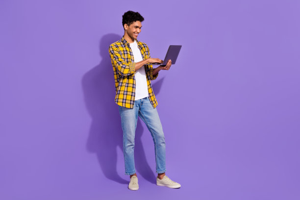 开朗的好男人的全长照片使用上网本的空白空间和空白隔离在紫色的背景图片下载