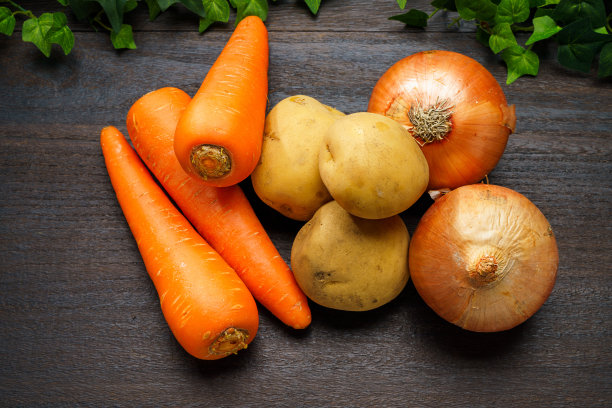 木桌上有未削皮的生土豆、洋葱和胡萝卜图片下载