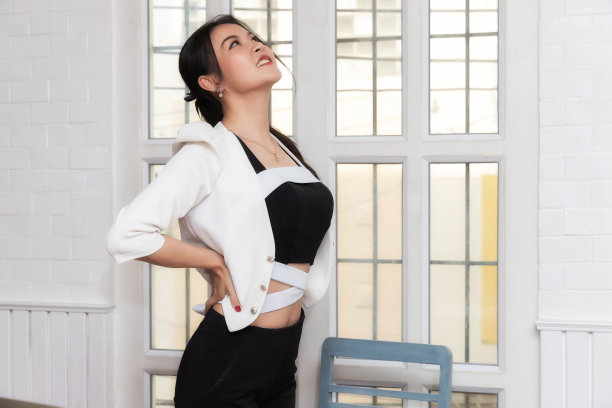 办公室综合症概念。女商人以不正确的姿势久坐工作后，扭曲身体以缓解疲劳和疼痛。图片下载