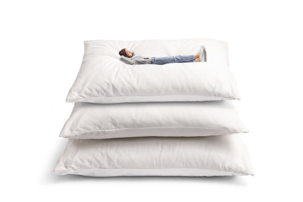 一个穿着牛仔裤的年轻女性躺在一堆枕头上的全身照片图片下载