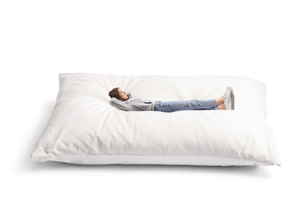 一个穿着牛仔裤的年轻女性躺在一个大枕头上的全身照片图片下载