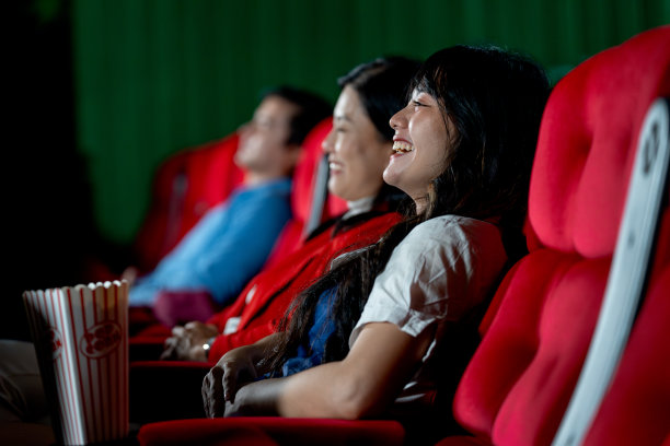 亚洲年轻的成年女性和她的妹妹坐在电影院的座位上，在假期或空闲时间的快乐和放松活动的概念中，看起来很开心，微笑着。图片下载