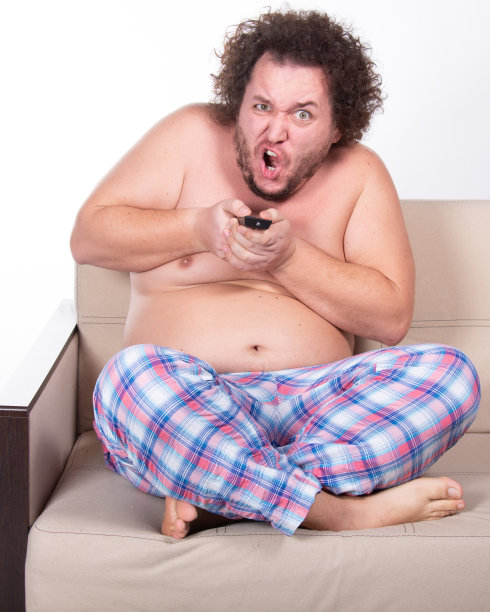 滑稽的胖子在家看电视。图片下载