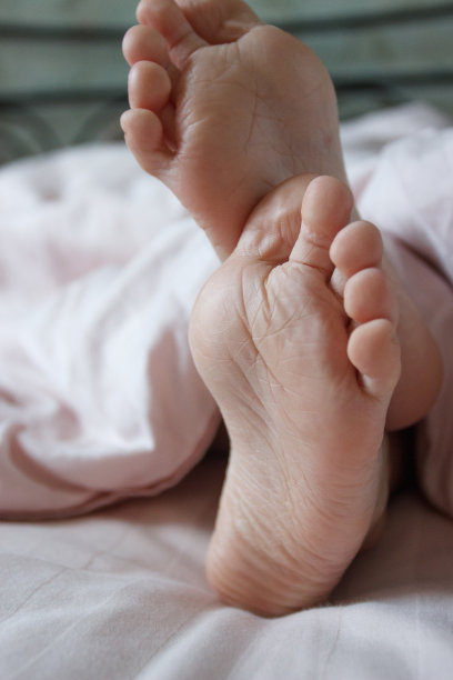 脚盖在床上的薄毯子下。睡眠或清醒的概念图片下载