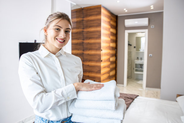 酒店房间里拿着干净毛巾微笑的女仆肖像。图片下载