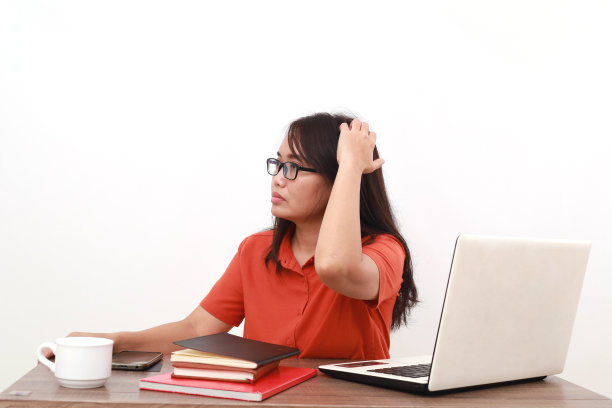 困惑的年轻亚洲女企业家抱着她的头，看着旁边。孤立于白色图片下载